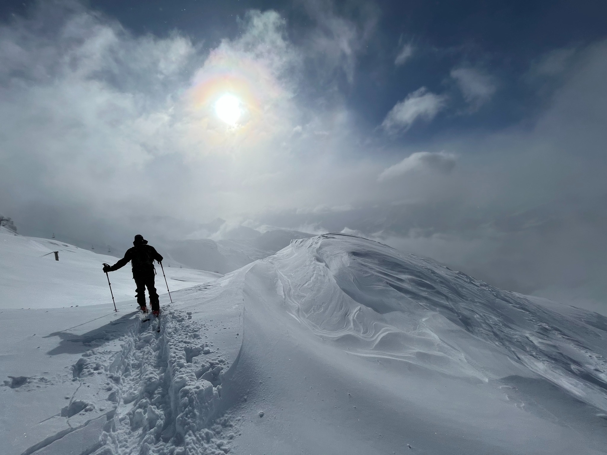 Ein Wanderer auf einer verschneiten Bergtour unter einem weiten Himmel.